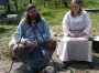 "Two Viking re-enactors in traditional summer day-wear garb tend a cook fire; Foteviken, Sweden."