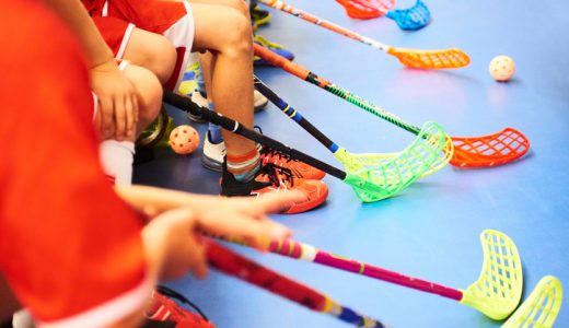 Children playing floorball. Boys holding floor ball sticks resting on the bench during a match